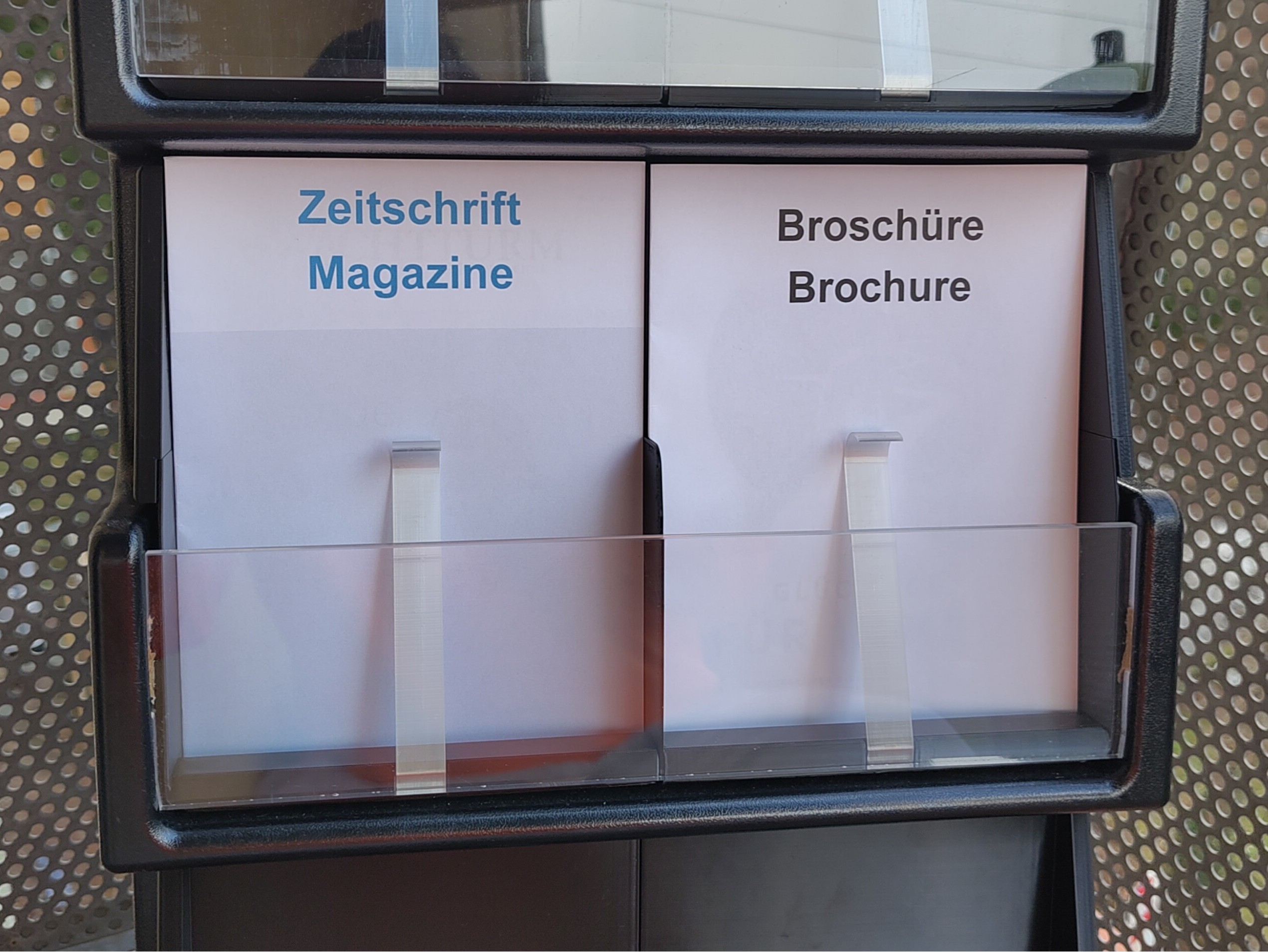 Darstellung eines mittleren Fachs im Trolley, dessen Zeitschriften mit Spangen gehalten werden.